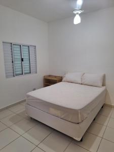 1 dormitorio blanco con 1 cama en una habitación en Recanto do Sossego, en Guarujá