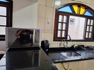 Um micro-ondas no balcão da cozinha com um homem lá dentro. em Recanto do Sossego no Guarujá