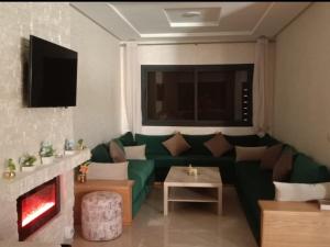 ein Wohnzimmer mit einer grünen Couch und einem Kamin in der Unterkunft Chalet villa QUE POUR LES FAMILLES in Imouzzer du Kandar