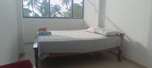 uma pequena cama num quarto com uma janela em Beach vibe hostel em Alappuzha