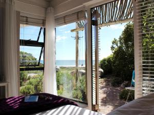 a bedroom with a window looking out at the ocean at Absolute Beach Accommodation in Stompneusbaai