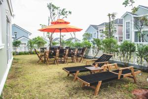 a group of tables and chairs with an umbrella at Seamoni Seaview Villa 01 - Novaworld Phan Thiết in Phan Thiet