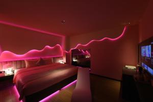 a bedroom with a bed with pink lighting and a tv at Chiic House 5 - Khách sạn tình yêu in Nha Trang