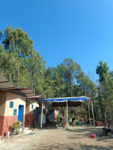 11 Gaon Mudhouse Homestay في لانسداون: مظلة زرقاء أمام المنزل