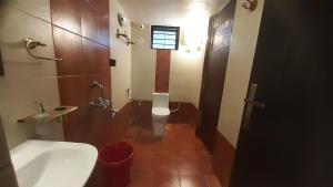 a bathroom with a white toilet and a sink at Cornwall for family in Madikeri