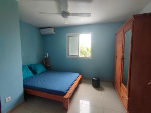 - une chambre bleue avec un lit et une fenêtre dans l'établissement Petite maison à 12mn du bassin de Manapany, à Saint-Joseph
