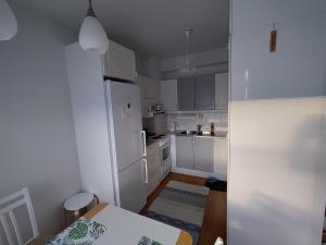 a white kitchen with a table and a refrigerator at Viihtyisä kaksio ydinkeskustassa in Lappeenranta