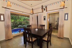 ein Esszimmer mit einem Tisch, Stühlen und einem Fenster in der Unterkunft Nature Village Resort in Pushkar