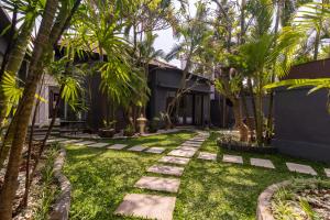 a garden with palm trees and a walkway at Casa Priya Canggu in Canggu