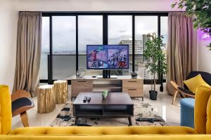 a living room with a yellow couch and a tv at Sunrise @ Gurney in George Town