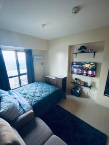 a bedroom with a bed and a couch and a television at Casa de Guapo - AYALA Serin East Taal View Condo in Tagaytay