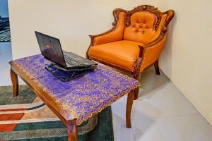 an orange chair with a laptop on a table at OYO 91707 Jannah Homestay Syariah in Dau