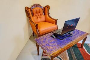 an orange chair and a laptop on a table at OYO 91707 Jannah Homestay Syariah in Dau