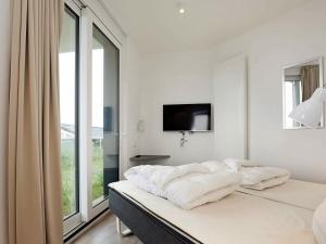 a white bedroom with a bed with a tv on the wall at Two-Bedroom Holiday home in Wendtorf 29 in Wendtorf