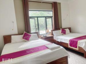two beds in a room with a window at Starlet Hotel Phong Nha in Phong Nha