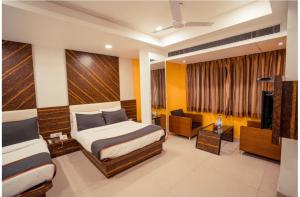 a hotel room with two beds and a couch at Kanchan Tilak in Indore
