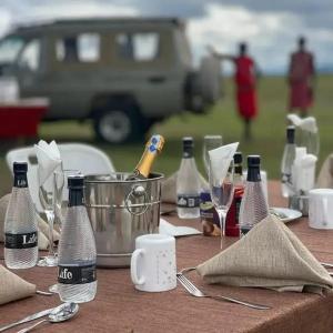 a table with bottles of champagne and glasses on it at MASAI MARA COTTAGES in Narok