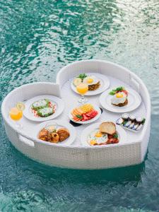 a circular table with plates of food in the water at Eden The Residence at The Sea Seminyak in Seminyak