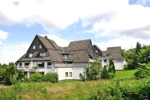 a large white house with a black roof at Apartment, Hahnenklee in Hahnenklee-Bockswiese