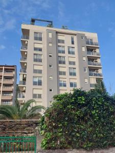 um edifício de apartamentos alto com um arbusto em frente em Nice apartment near Old Town and sea em Budva