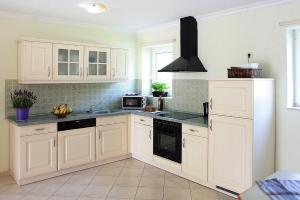 a kitchen with white cabinets and black appliances at Cottages at the Kummerower See, Verchen in Verchen