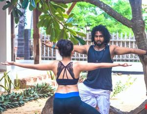 un hombre y una mujer haciendo yoga en un árbol en Ajith Putha Grand, en Madampe