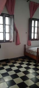 a bedroom with a bed and two windows and a checkered floor at My house in Rabat
