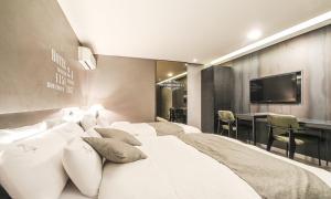 een slaapkamer met een groot wit bed en een televisie bij Jamsil 2.4 Hotel in Seoul
