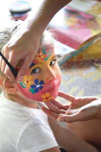 Una mujer pintando su cara con una pintura de la cara de una flor en VONRESORT Elite & Aqua - Ultra All Inclusive & Kids Concept, en Side