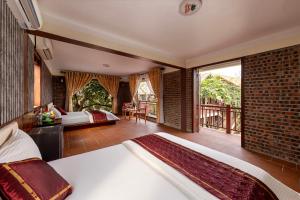 a bedroom with two beds and a balcony at Tam Coc Ngoc Linh Bungalow Ninh Bình in Ninh Binh