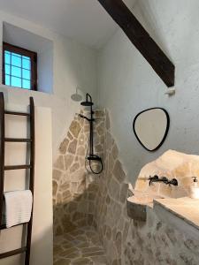 Baño de piedra con lavabo y espejo en Casa Rural La Chocolateria, en Horche