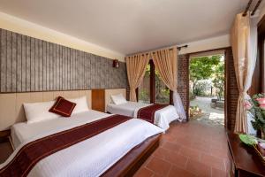 a bedroom with two beds and a balcony at Tam Coc Ngoc Linh Bungalow Ninh Bình in Ninh Binh