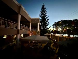 a building with tables and umbrellas in front of a tree at Sunset Boulevard Riverlodge in Paarl