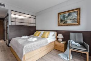 a bedroom with a bed and a chair at Apartamenty Premium - kompleks Deo Plaza in Gdańsk