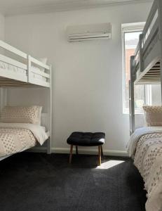 Luxury stay in Williamstown في ويليامزتاون: غرفة بيضاء مع سريرين بطابقين ومقعد