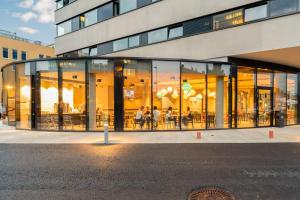 un edificio de cristal con gente sentada dentro de él en harry's XL Hotel, en Salzburgo