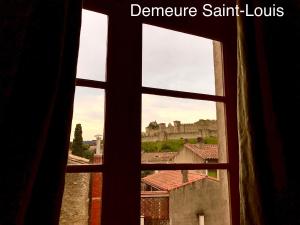 ein offenes Fenster mit Blick auf ein Schloss in der Unterkunft Demeure Saint Louis, Cité 10mn à pieds, PARKING Privé, BORNES 7,2 KW, AC, FULL WIFI in Carcassonne