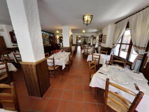 un restaurante con mesas y sillas con mesas blancas en Hotel Rural Pepe Alvarez, en Trevélez