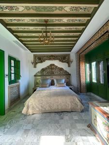1 dormitorio con 1 cama grande y lámpara de araña en Dar Waya, en Mahdia