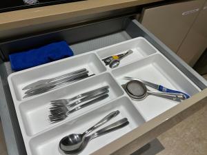 a white tray with silver utensils in a drawer at European studio apartment at Hiranandani thane in Thane
