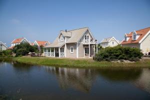 a house sitting next to a body of water at Summio Duynparc De Heeren van 's-Gravensande in Vluchtenburg