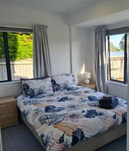 1 dormitorio con 1 cama con edredón de flores y 2 ventanas en Wharewaka Haven, en Taupo