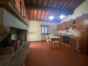 a large kitchen with a table and a stone fireplace at Casolare il Moro in Monte San Savino