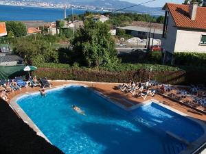 duży basen z ludźmi siedzącymi na krzesłach wokół niego w obiekcie Hostal Las Vegas w mieście Cangas de Morrazo