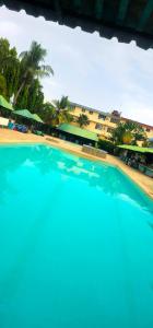 ein blauer Pool mit Palmen im Hintergrund in der Unterkunft ASINS HOLIDAY INN HOTEL in Ukunda