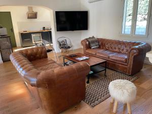 sala de estar con 2 sofás de cuero y TV en Villa proche d'Avignon., en Le Pontet