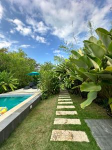 a garden with a pathway next to a swimming pool at Larue Pocket Villa in Calatagan