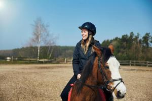 een vrouw op een paard in een veld bij Holiday Resort Van der Valk, Linstow in Linstow