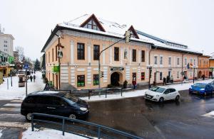 een straat met auto's geparkeerd voor een gebouw bij Penzión Gurmen in Stará Ľubovňa