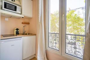 a kitchen with a microwave and a window with a balcony at Appartement coloré Wagram - II in Paris